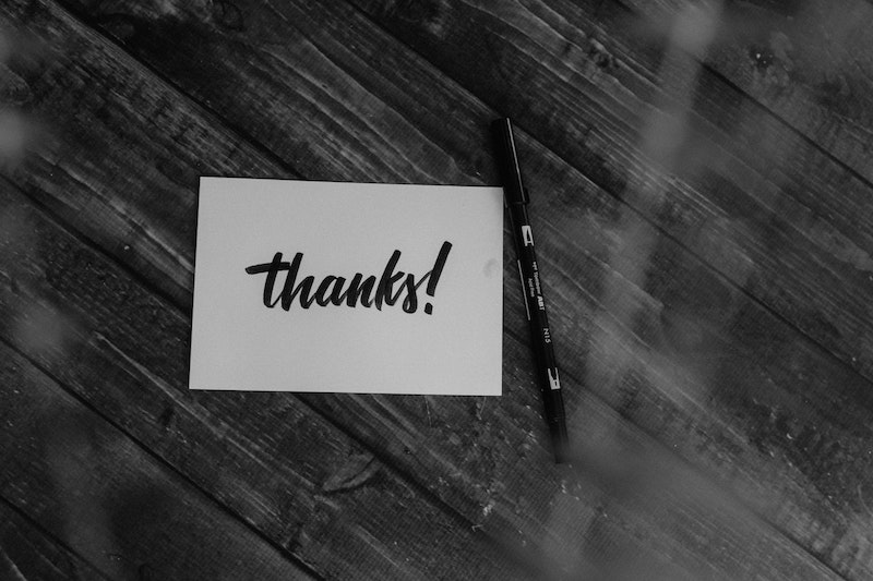 Table with notecard saying "thanks!" with pen next to it.